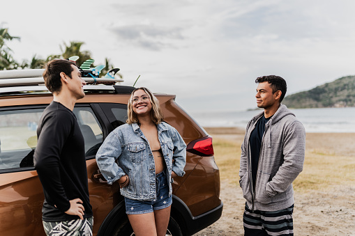 Surfer friends talking when they arrive with car on the beach