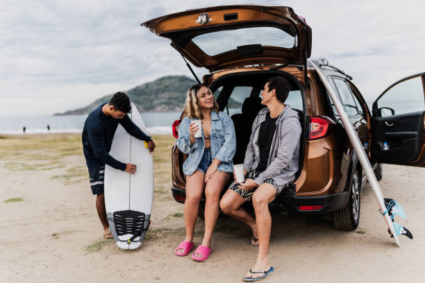 istock Surfer friends talking sitting on car trunk at the beach 1889958050