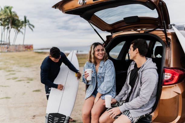 istock Surfer friends talking sitting on car trunk at the beach 1889963748