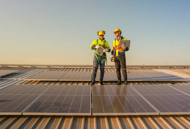istock Front view of two Caucasian technician workers stand on rooftop and discuss about the maintenance solar cell panels on rooftop of factory or the building. Green and sustainable energy concept. 1889974269