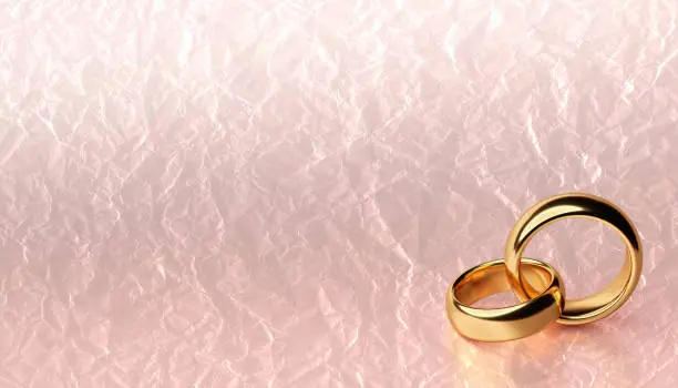 Banner of two wedding gold rings lie on each other with blank background with crumpled paper texture