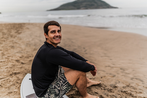 Portrait of a mid adult surfer man sitting at the beach