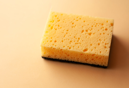 Cleaning sponge on a peach fuzz color background. Cleaning concept, cleaning service.Top view