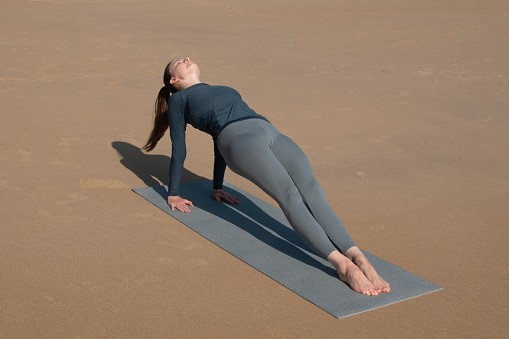 Young woman practicing yoga on the beach. Concept of healthy lifestyle and relaxation.