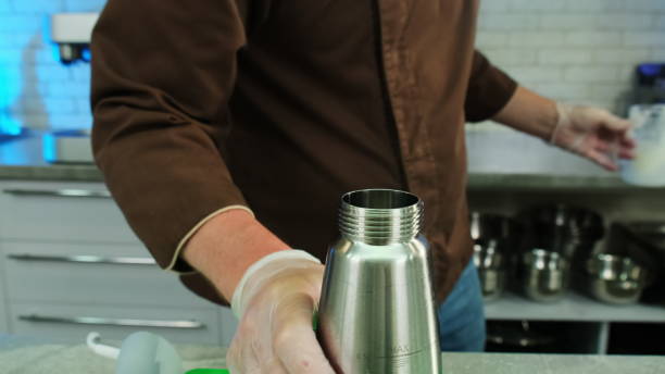 istock Chef screws lid of whipping siphon on table closeup 1890062788