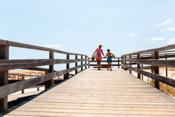 mãe e filho caminhando juntos na praia no algarve portugal - beach family boardwalk footpath - fotografias e filmes do acervo