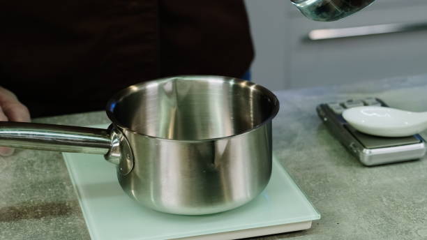 istock Man pours water from measurement cup into saucepan on scale 1890090241