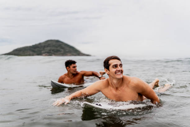 istock Surfer friends surfing on the beach 1890107745