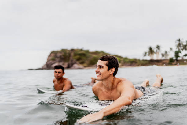 istock Surfer friends surfing on the beach 1890107784