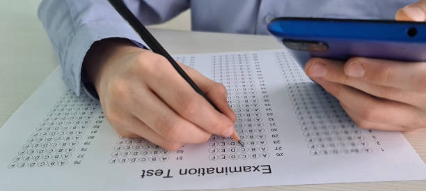 istock Student child holding smartphone during control exam test at school and cheating on the exam 1890154753