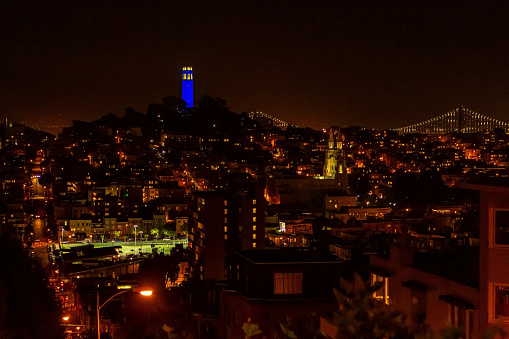 View of the Coit Tower at night, from Russian Hill, in San Francisco. San Francisco Cityscape at Night Panorama. View of Coit Tower and St. Peter and Paul church at night, from Lombard street.