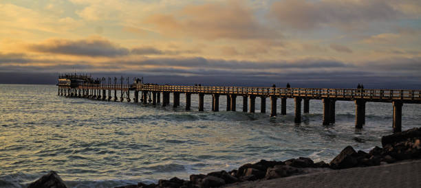 Swakopmund Pier jutting out into Atlantic Ocean against a stormy orangey blue sky