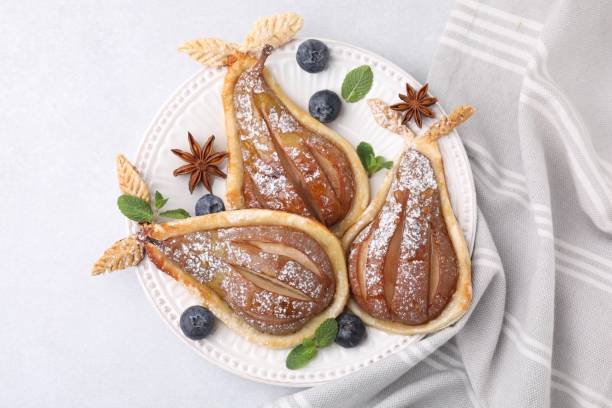 istock Delicious pears baked in puff pastry with powdered sugar on light table, top view 1890282197