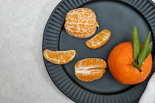 Fresh ripe mandarine in black ceramic plate