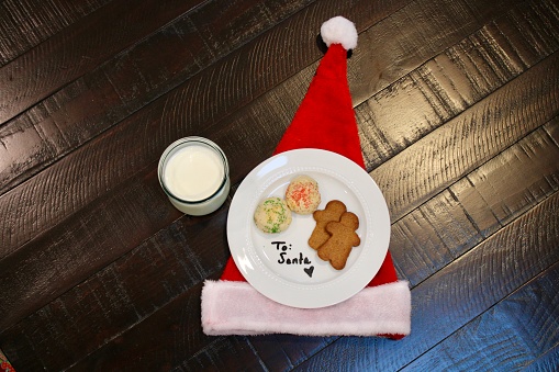 A place setting with a glass of milk, a plate with a handwritten note, ricotta cookies, and gingerbread men.