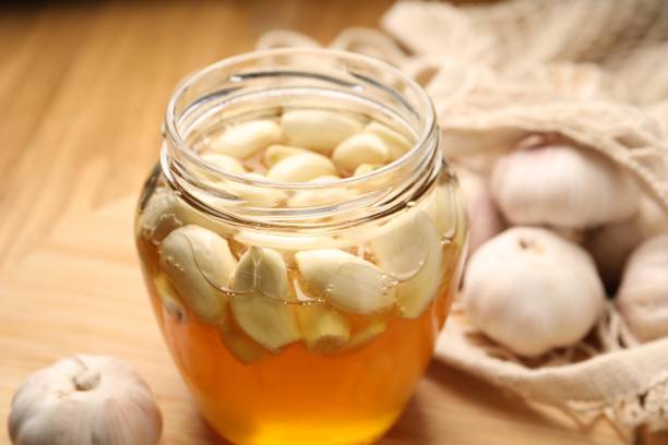 istock Honey with garlic in glass jar on table, closeup 1890298051