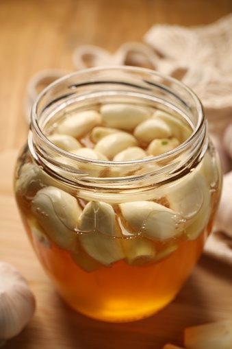 Honey with garlic in glass jar on table, closeup