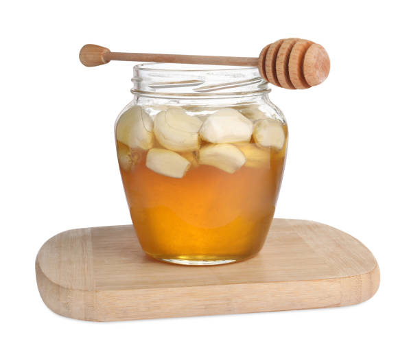 istock Honey with garlic in glass jar and dipper isolated on white 1890300636