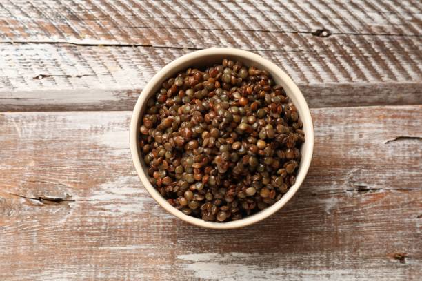 istock Delicious lentils in bowl on wooden table, top view 1890318433