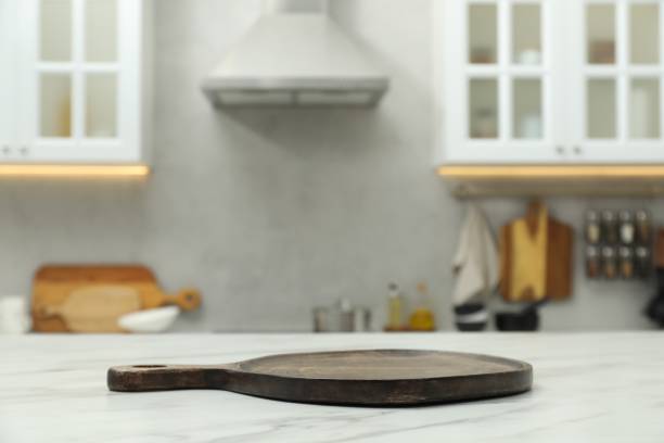 istock Wooden cutting board on white table in kitchen. Space for text 1890324065