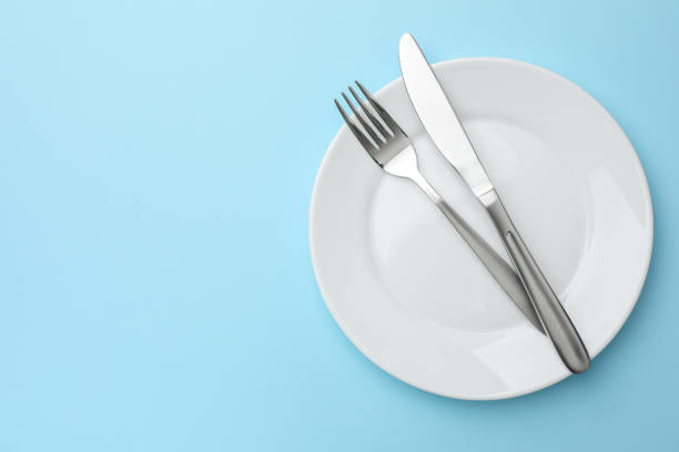 istock Clean plate, fork and knife on light blue background, top view. Space for text 1890325613