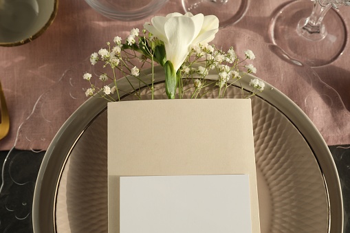 Stylish table setting. Plates, blank card and floral decor, top view