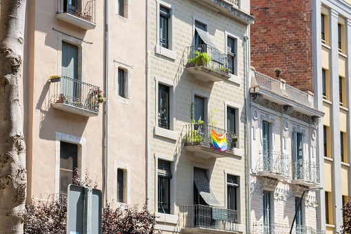 Flag with rainbow colors on the balcony of old house with much beautiful flowers in Spain city.