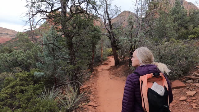 Mature female hiker explores red rock desert lands