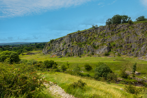 Sheer rock face rising up from grasslands in the Yorkshire Dales National Park, England.