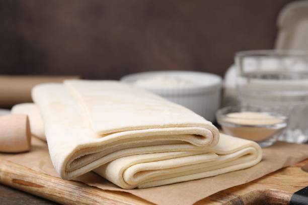 istock Raw puff pastry dough on wooden table, closeup 1890368907