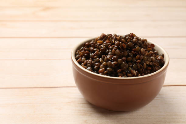 istock Delicious lentils in bowl on wooden table, closeup. Space for text 1890369941