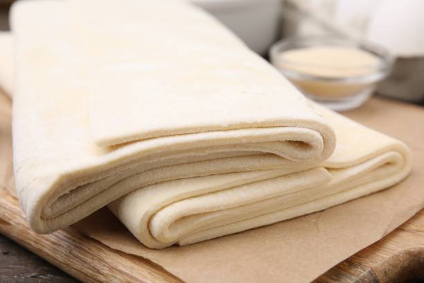 istock Raw puff pastry dough on wooden table, closeup 1890370987