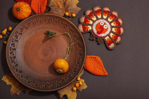 Autumn table setting. Thanksgiving cutlery, traditional fall decor, flat lay. Festive cozy mood, handmade crocheted turkeys and leaves, brown background, top view