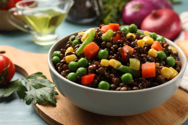 istock Delicious lentils with vegetables on light blue table, closeup 1890372046