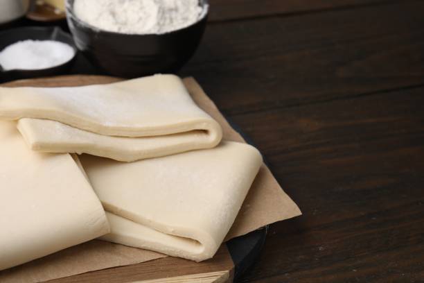istock Raw puff pastry dough on wooden table, closeup. Space for text 1890374144
