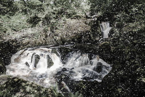 Digital composite image of blurred water rushing over a waterfall in winter in the Yorkshire Dales National Park, England.