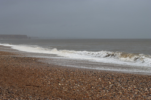 Stormy sea breaking onto a pebble beach in winter