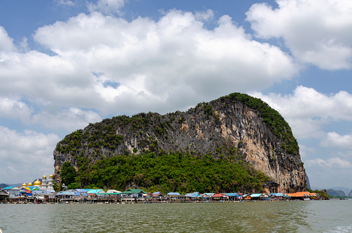 A captivating image of the Floating Village in Ao Phang Nga National Park, where stilted houses and structures sit atop tranquil waters. This unique community, nestled among stunning limestone karsts and emerald seas, highlights the traditional lifestyle harmoniously intertwined with the natural beauty of the region.