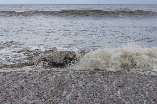 Foamy sea waves breaking onto a beach