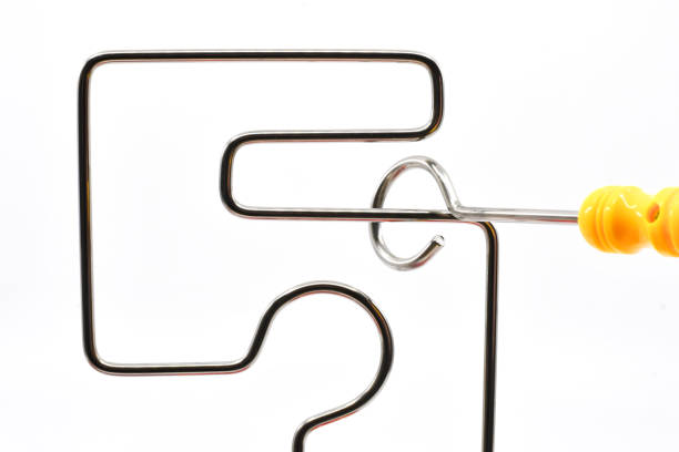 Small wand being moved around a wire frame game without touching the metal. No people. Games concept.