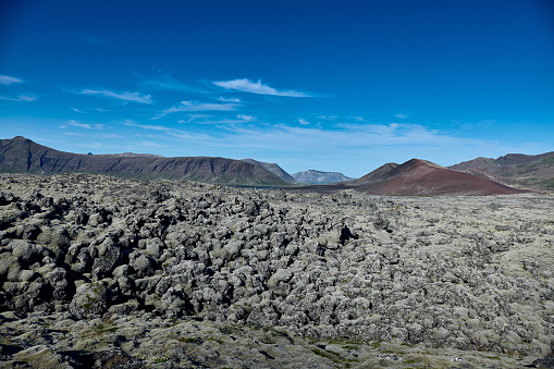 In the foreground a lava field covered with moss, in the background mountains.Helgafellssveit, Iceland.
