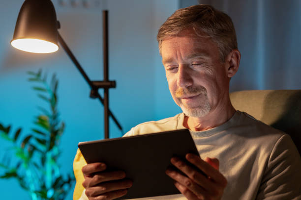 istock 50 year old man sitting on the sofa using a digital tablet 1890458382