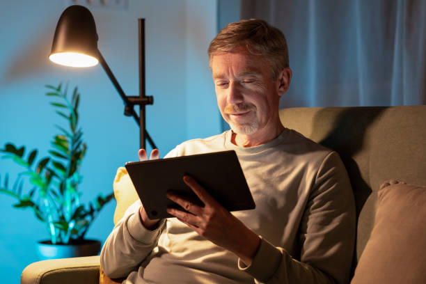 istock 50 year old man sitting on the sofa using a digital tablet 1890458389