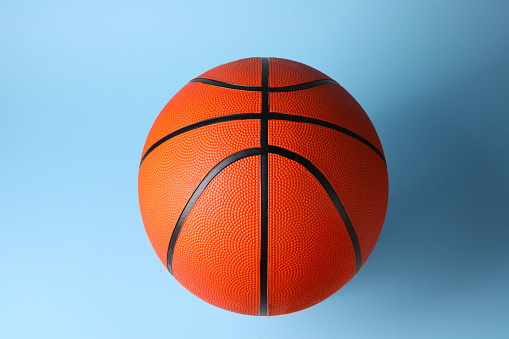 One orange basketball ball on light blue background, top view