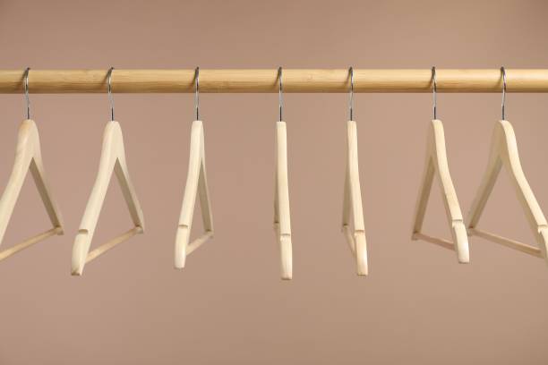 istock Empty clothes hangers on wooden rack against light brown background 1890473872