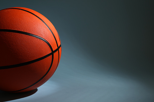 One orange basketball ball on dark grey background, closeup. Space for text