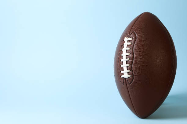 istock American football ball on light blue background. Space for text 1890473945