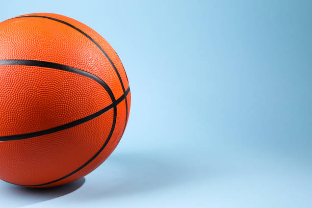 istock One orange basketball ball on light blue background, closeup. Space for text 1890473948