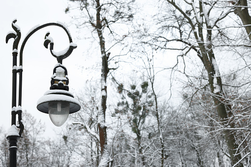 Beautiful street light with snow against sky in winter, space for text