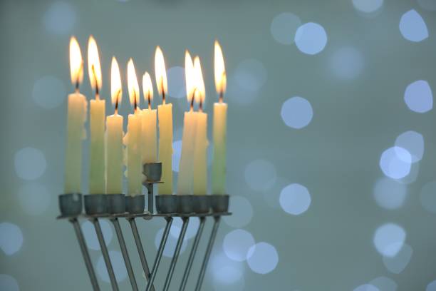 istock Hanukkah celebration. Menorah with burning candles against blurred lights, space for text 1890505137